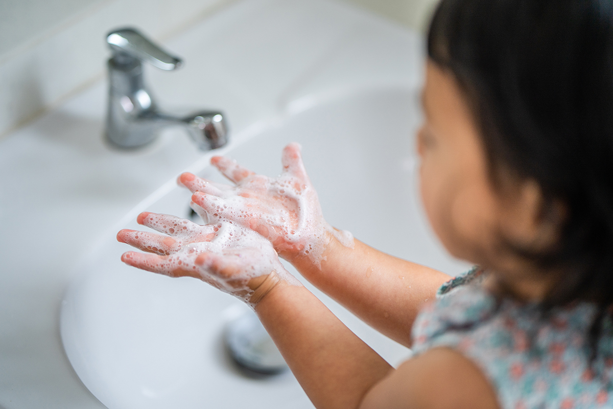 Young girl washing her hands.